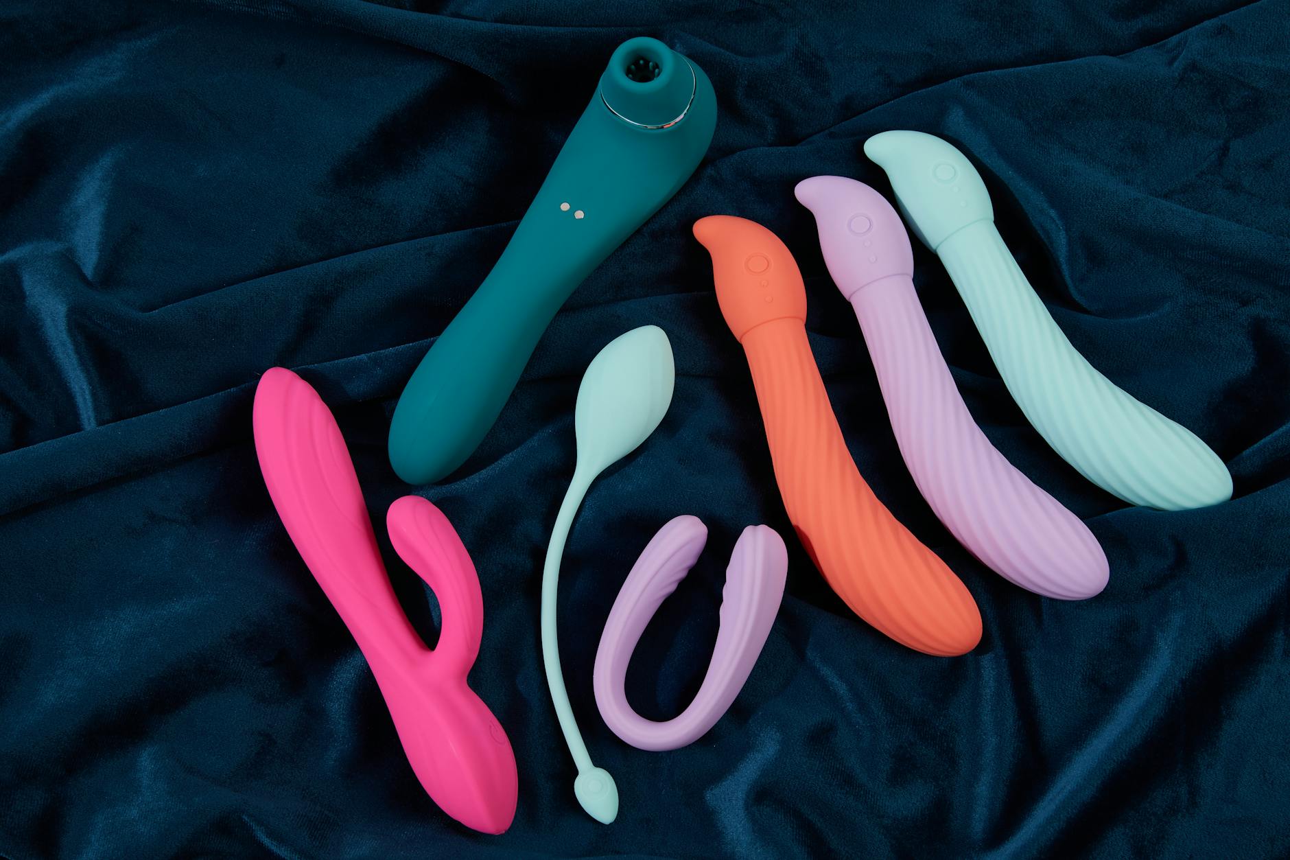 Hand holding a blue silicone vibrator against a purple background, representing self-pleasure and modern intimacy