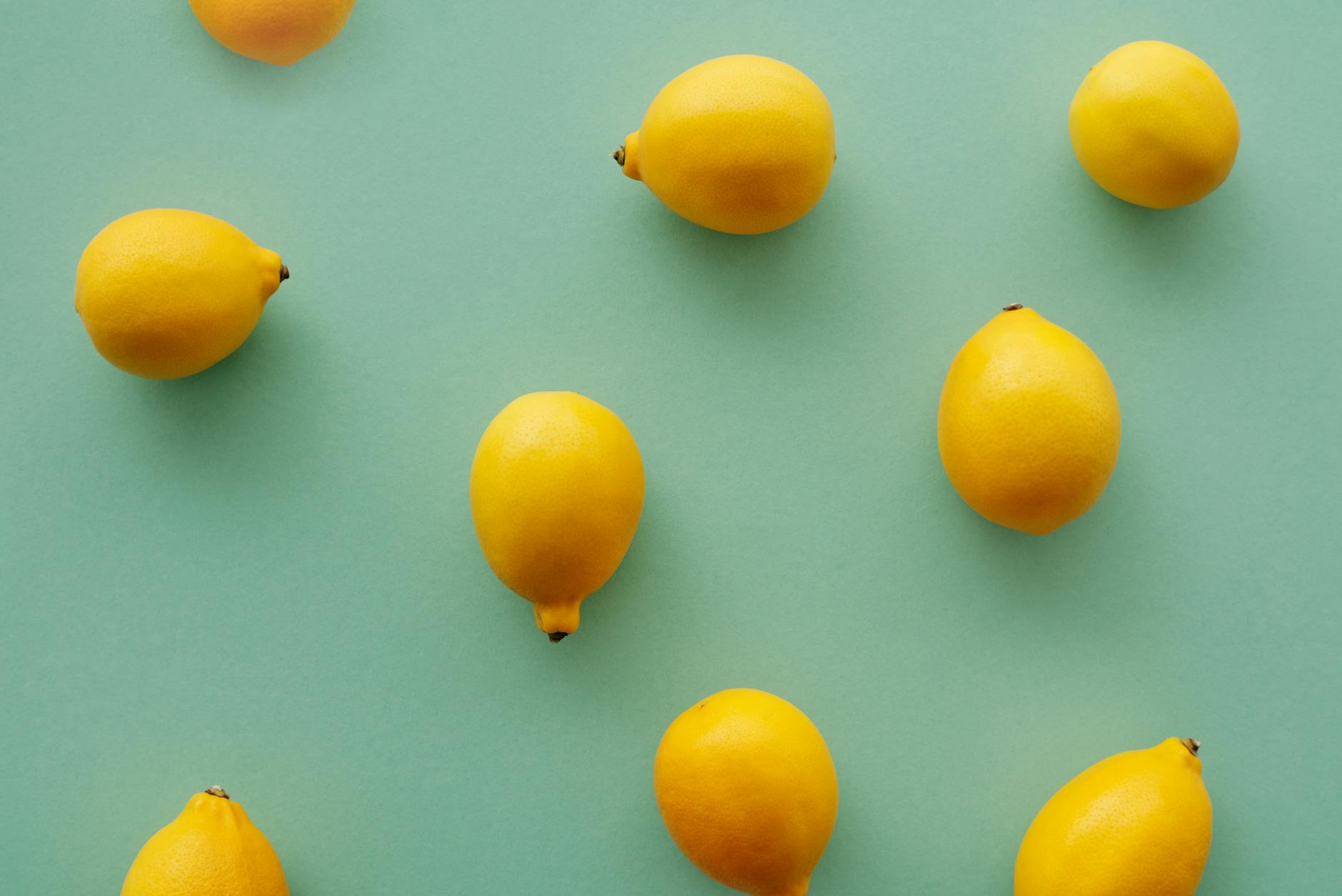 Bright yellow lemons arranged on a pastel green background, symbolizing fresh starts and natural pleasure