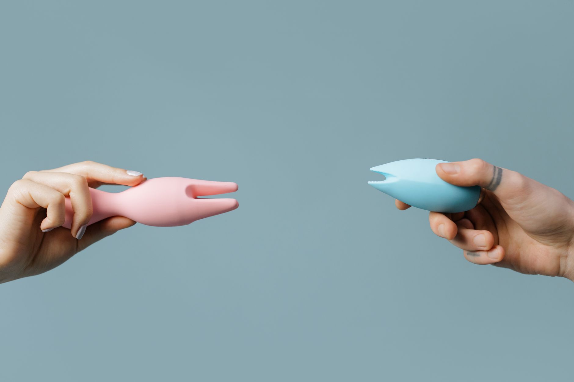 A blue silicone lemon clitoral vibrator held in hand against a purple background, symbolizing self-care and reclaimed pleasure