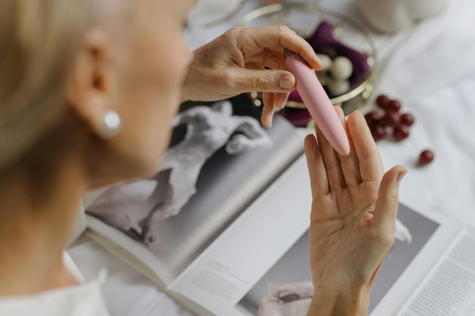 Close-up of a woman holding a pink vibrator, emphasizing intimate self-care during low-energy periods.
