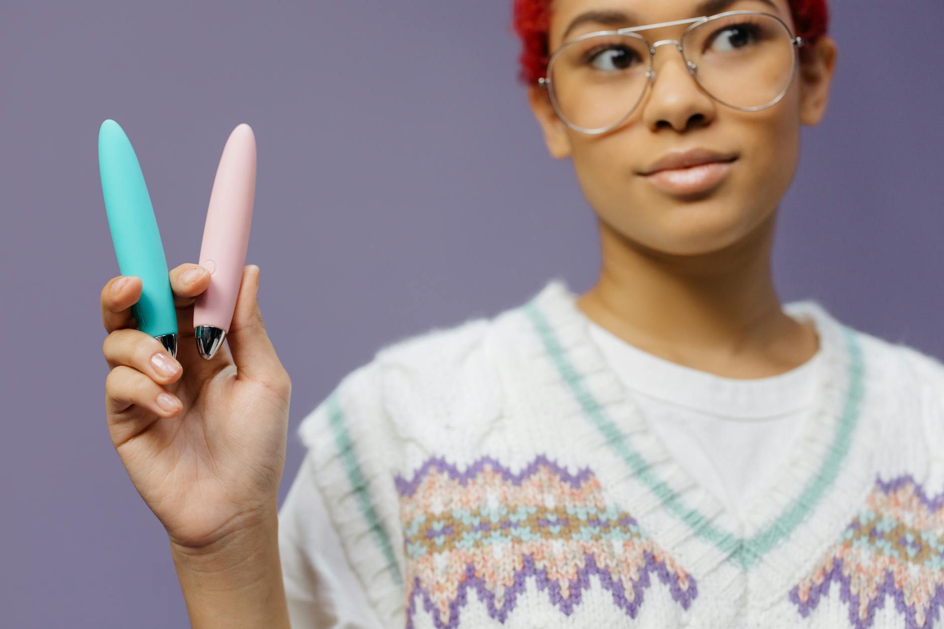 A person holding a lemon clitoral vibrator against a purple background, showcasing the design.