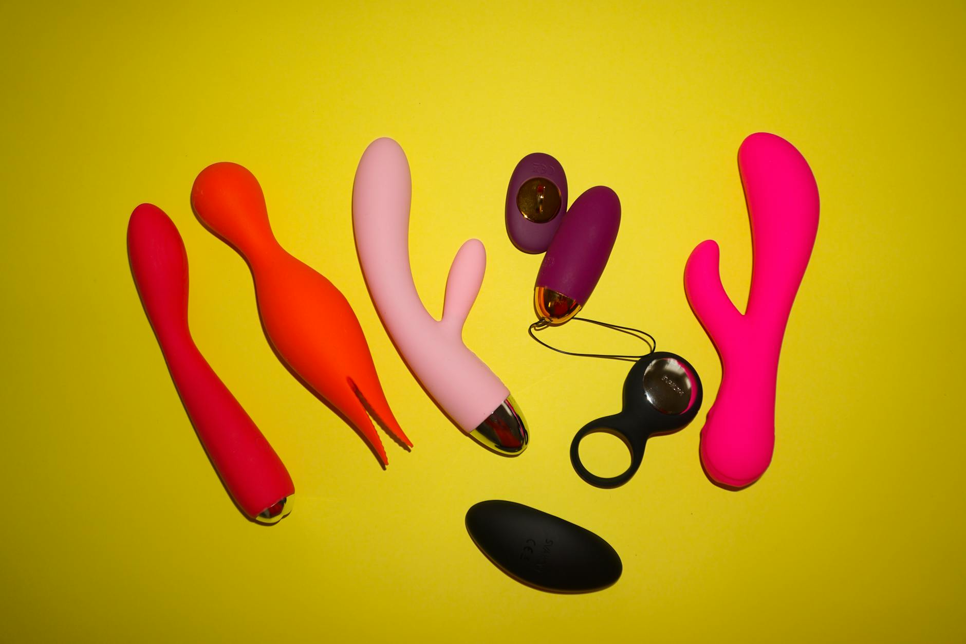 Hands holding a blue clitoral vibrator against a purple background, representing self-care during postpartum recovery