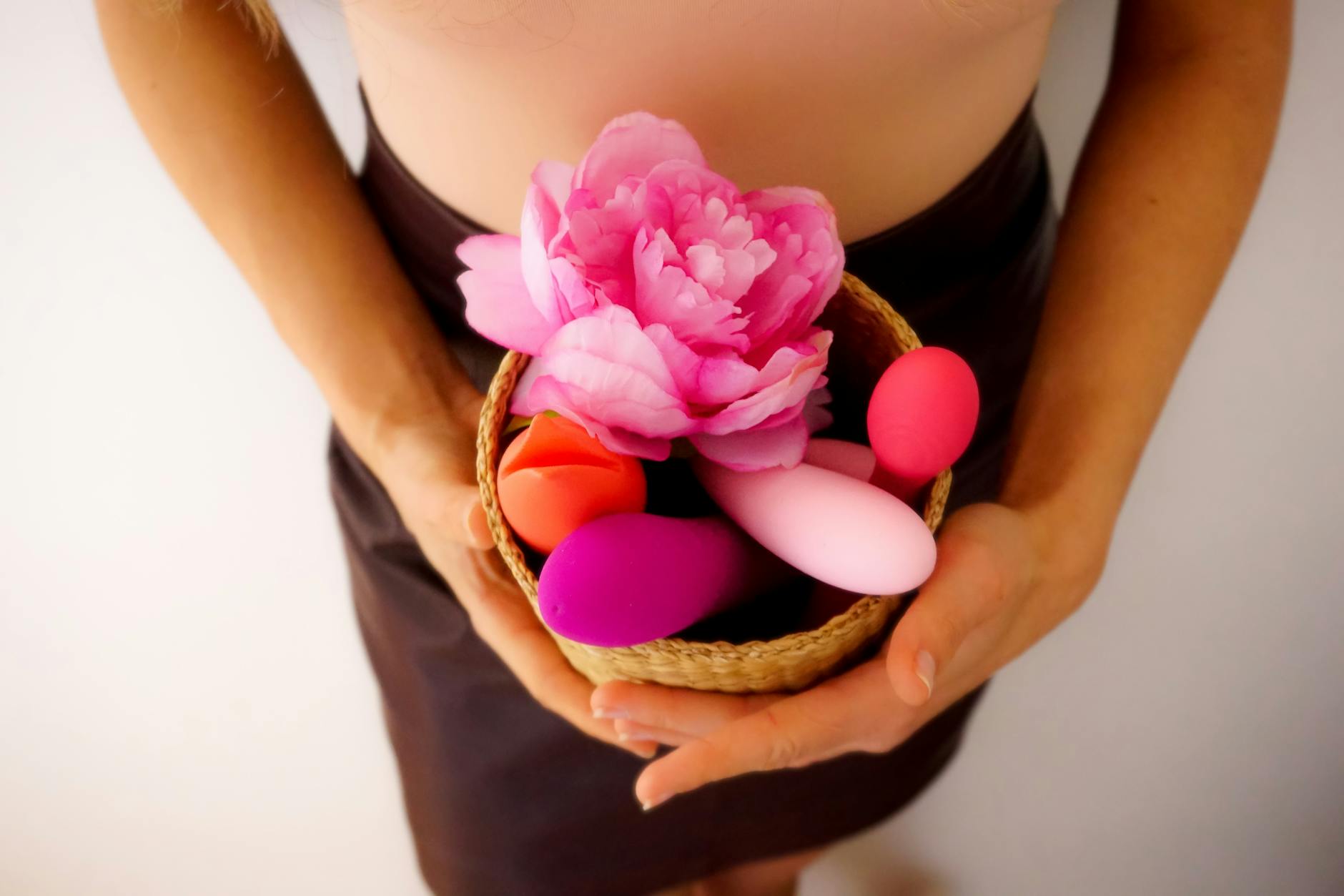 Hands holding pastel-colored silicone toys for pleasure and wellness